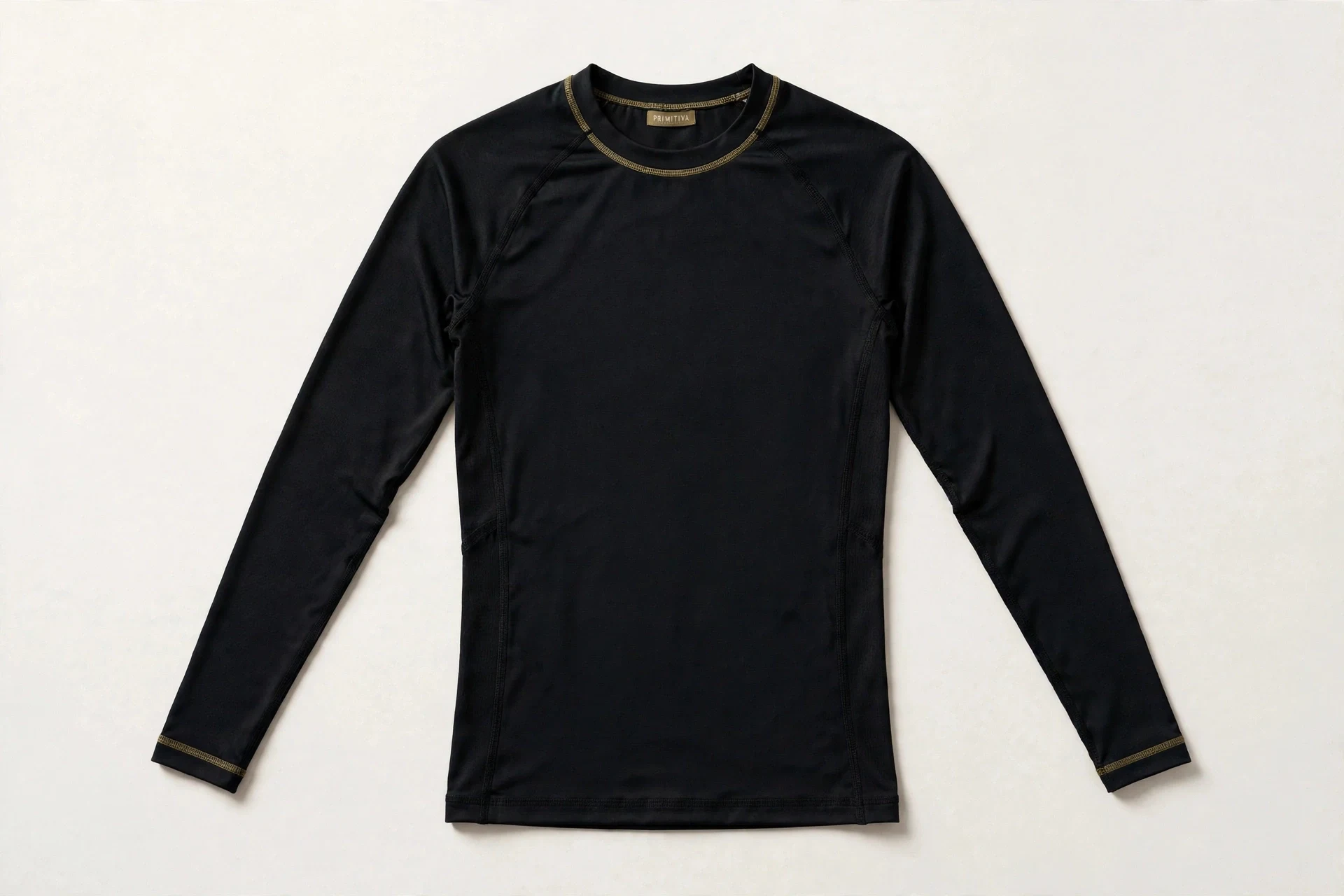 Primitiva long-sleeve compression shirt in black and gold with the Primitiva neck tag