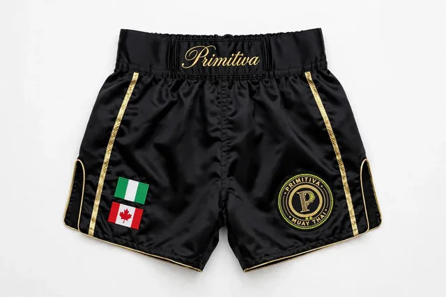 Primitiva short de combat BG — Héritage en noir et doré avec les drapeaux du Nigeria et du Canada et inscription sur la ceinture