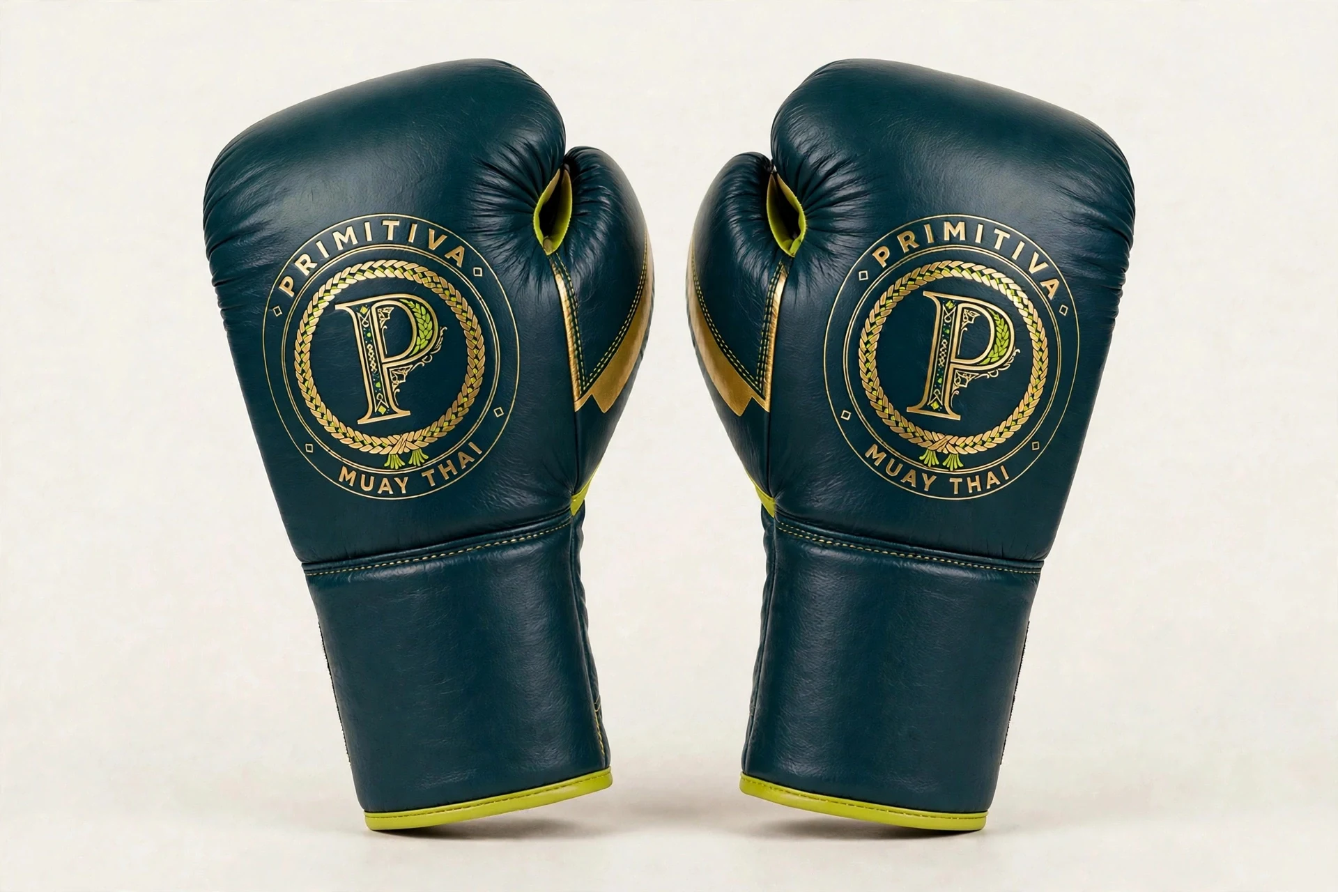 Primitiva Nak Muay lace-up gloves in teal and gold — front view: the emblem on the fist