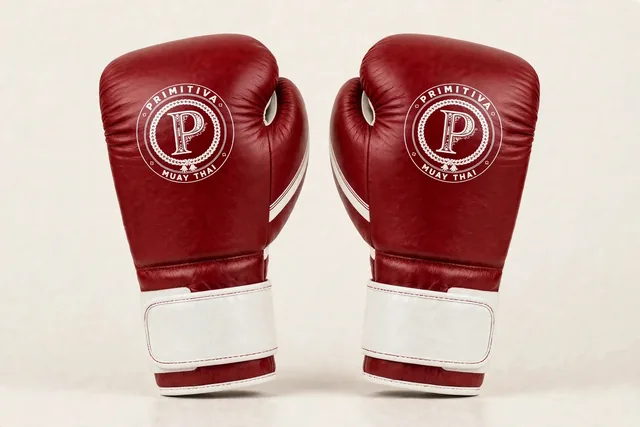 Gants d’entraînement Primitiva WR en rouge et blanc — vue de face : l’emblème sur le poing, sangle velcro rouge